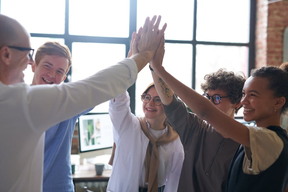 pexels photo 3184427 3184427 A diverse team of professionals celebrating success with a high five in a modern office.